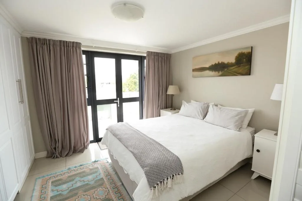 Bright modern bedroom with queen bed, garden view doors, and neutral decor