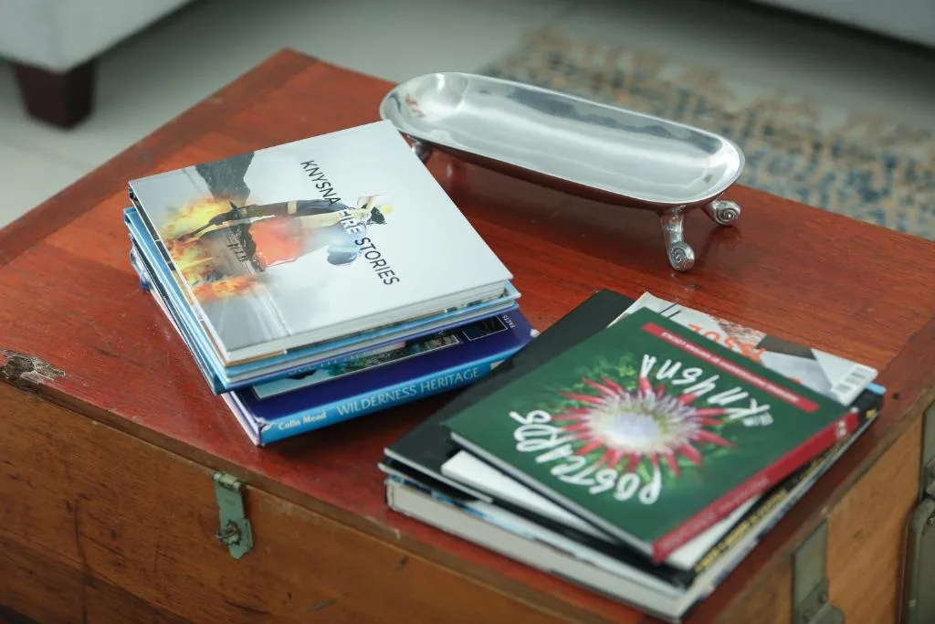 Decorative books and silver trinket tray on wooden side table