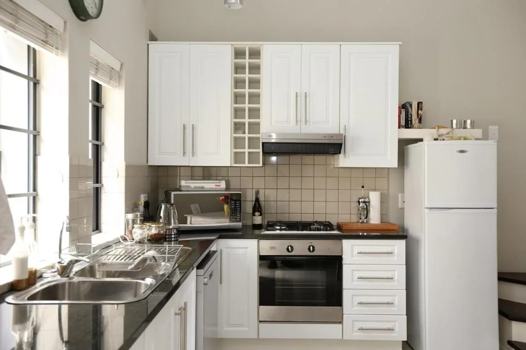 Modern kitchen with white cabinetry, stainless steel appliances, and dark countertops