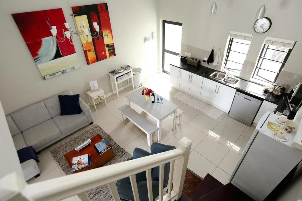 Open-plan lounge and kitchen with gray sofa, white dining table, and modern appliances