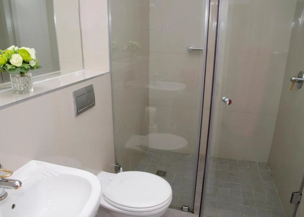 Modern bathroom with vanity, toilet, and frameless glass shower enclosure