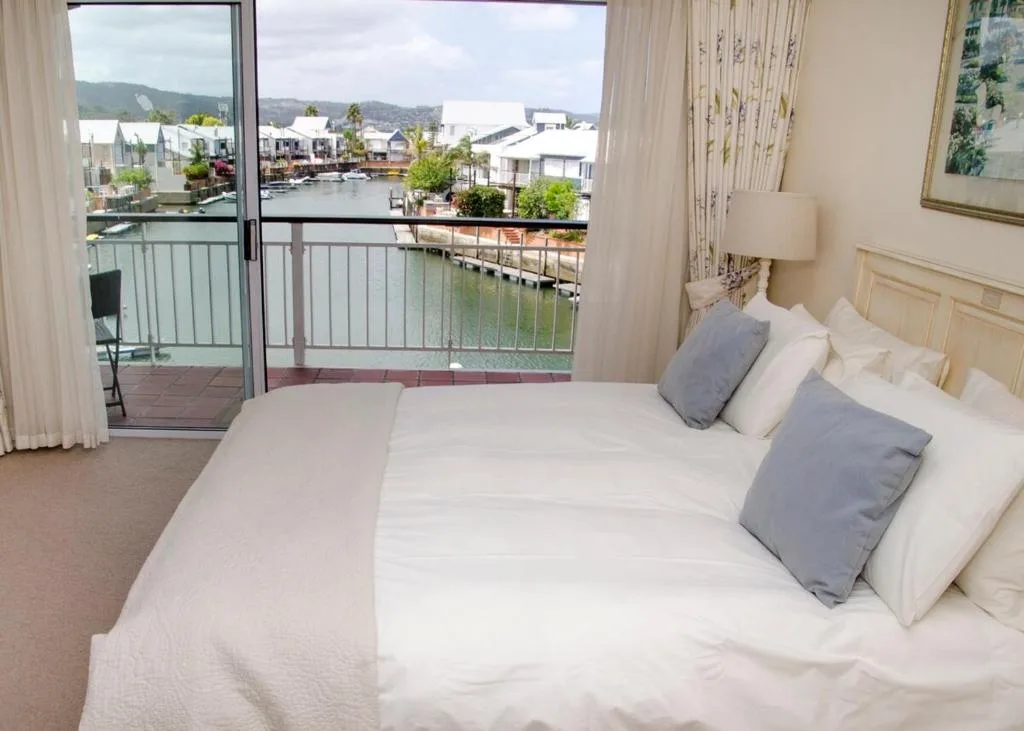 Spacious bedroom with waterfront lagoon views through glass doors