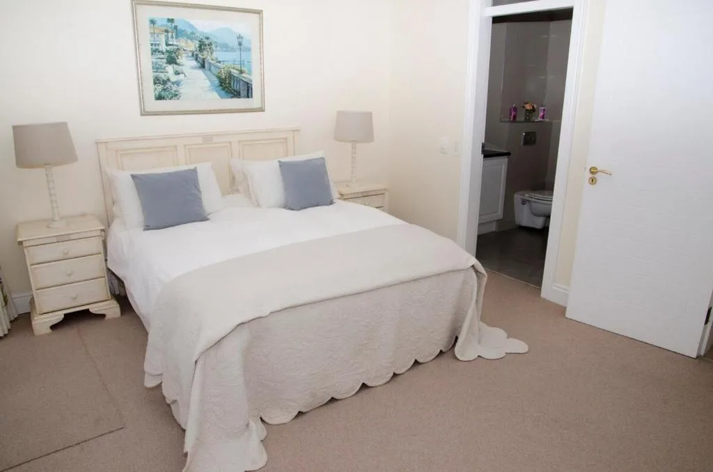 Bright bedroom with double bed, blue cushions, and ensuite bathroom access