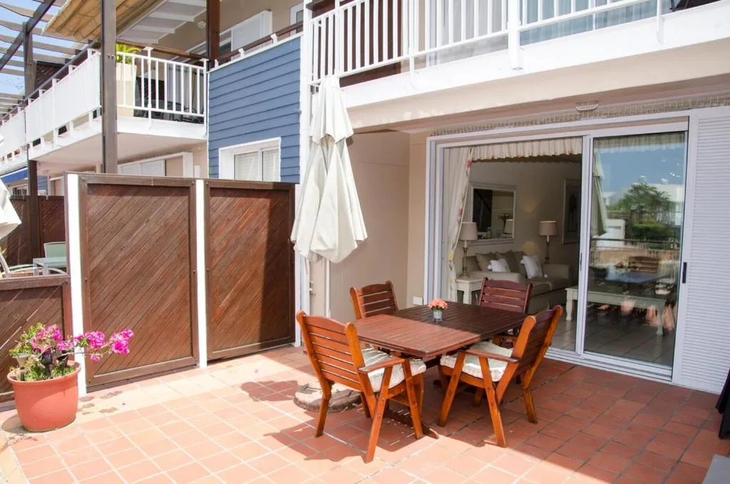 Outdoor patio with wooden dining table and chairs overlooking lagoon