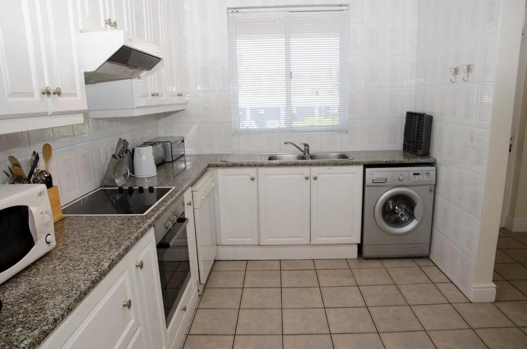 Modern kitchen with white cabinetry, granite counters, and integrated washing machine