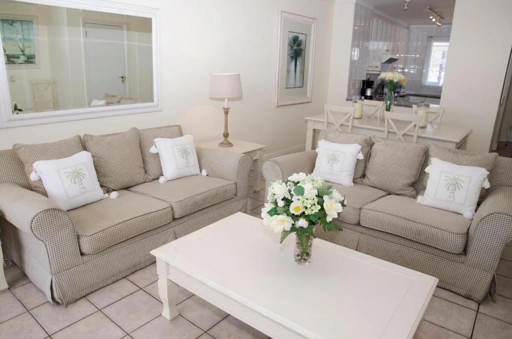 Bright lounge with two beige sofas, white coffee table, fresh flowers