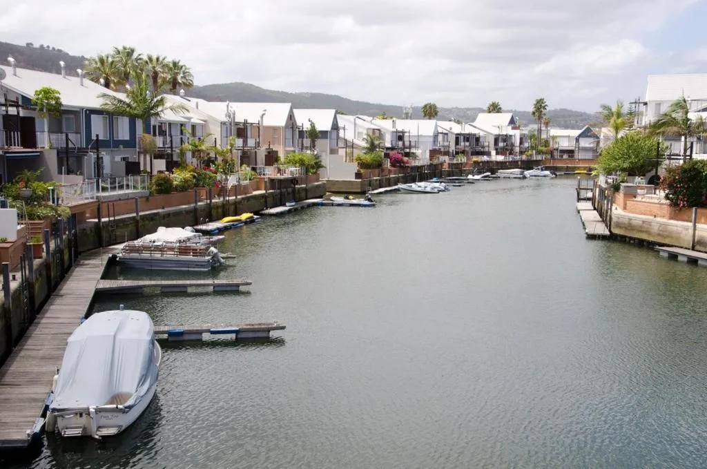 Serene lagoon waterfront with moored boats and mountains beyond