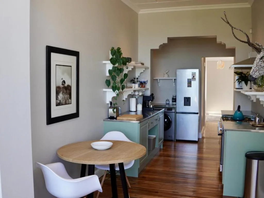 Modern kitchen with turquoise cabinetry, stainless steel appliances, and dining table