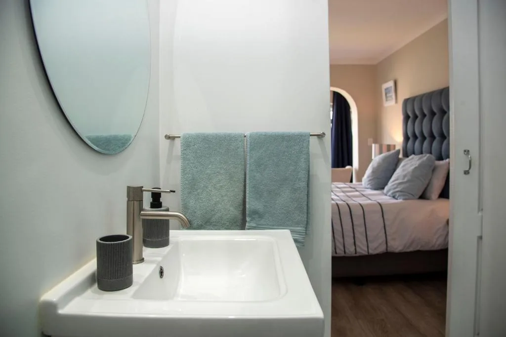 Modern bathroom vanity with round mirror and green towels displayed