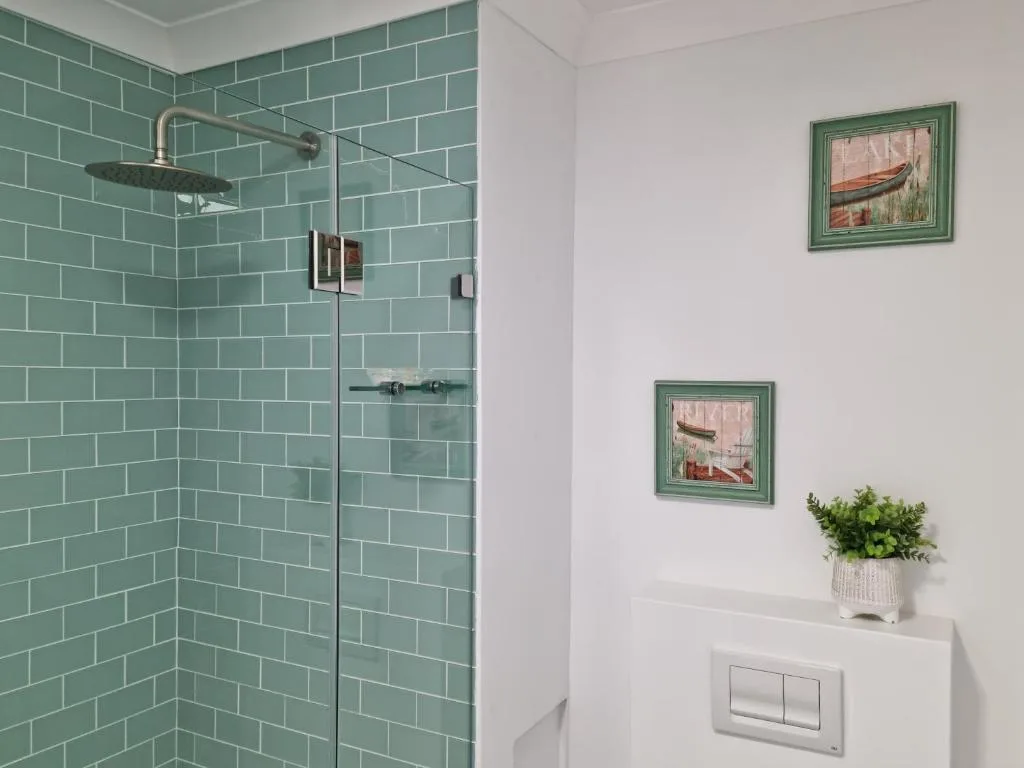 Modern bathroom with turquoise subway tile shower and decorative framed artwork