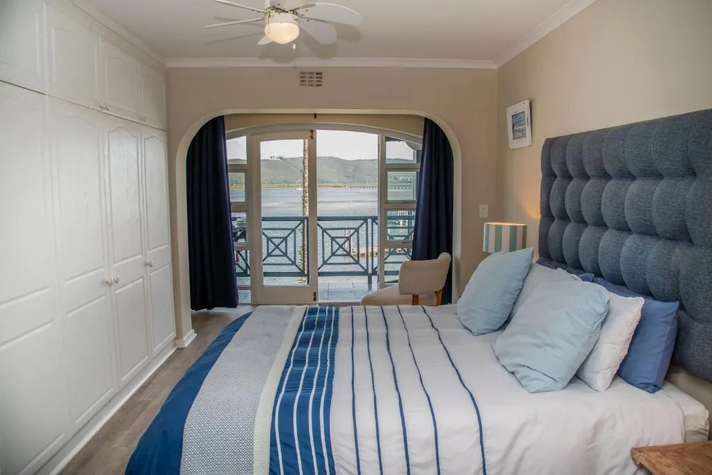 Bedroom with upholstered headboard, water view through glass doors and balcony