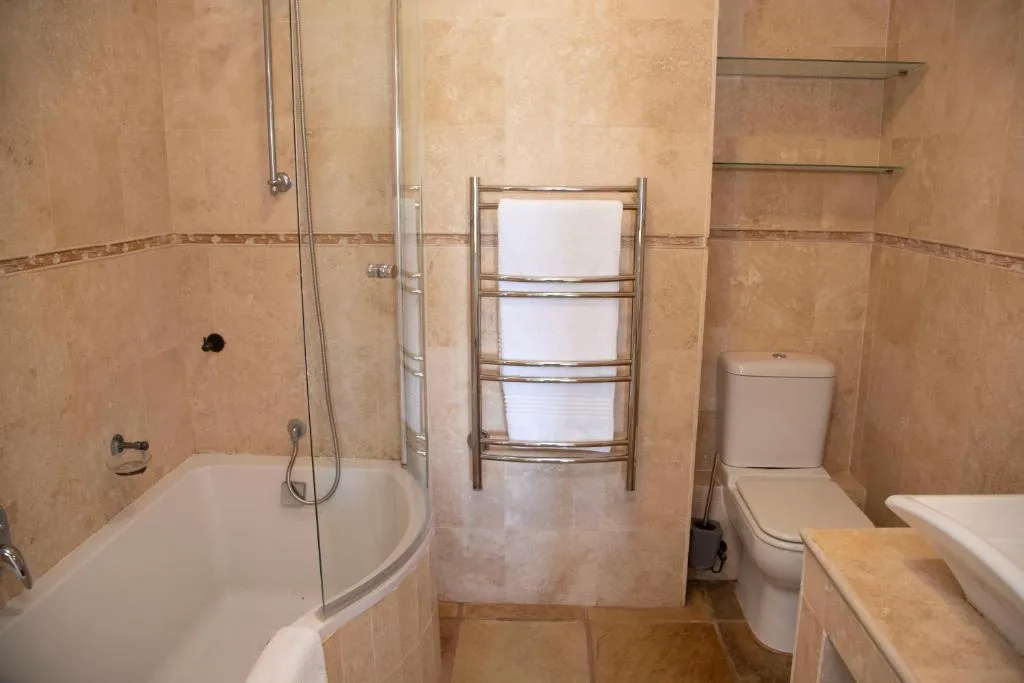 Spacious bathroom with corner bath, walk-in shower, heated towel rail, toilet
