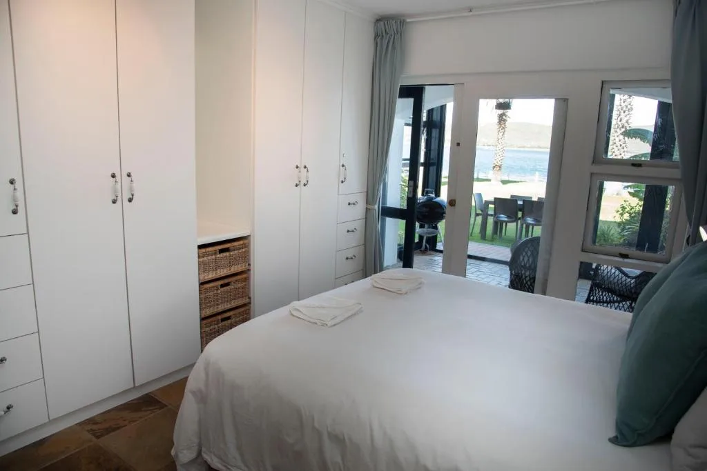 Bright bedroom with white built-in wardrobes and ocean views through glass doors