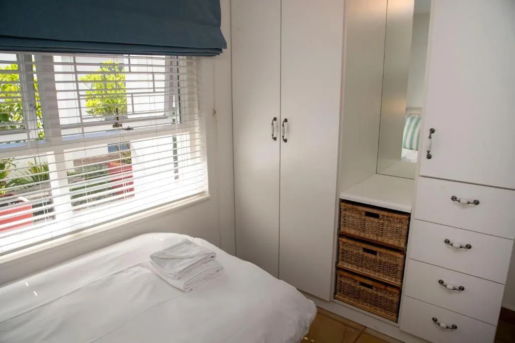 Bright bedroom with white built-in wardrobes and woven storage baskets