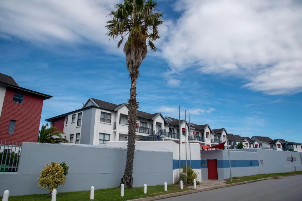 Modern white and red apartment buildings with palm tree and manicured entrance
