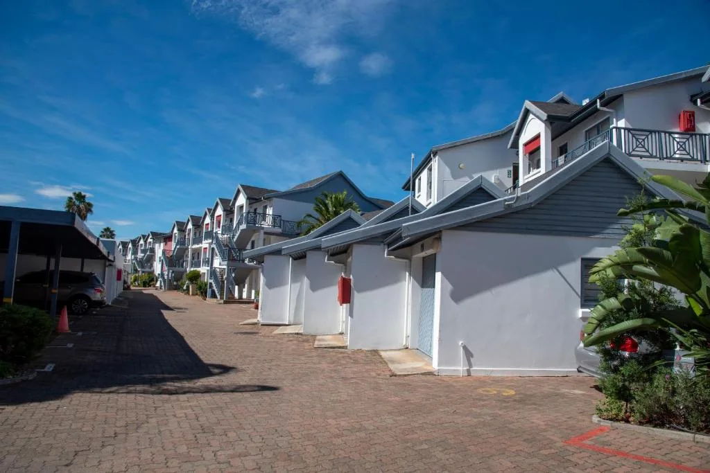 Row of white contemporary townhouses with brick paved driveway under blue sky