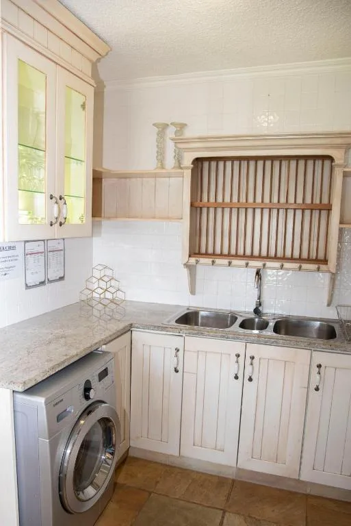 Bright kitchen with white cabinetry, granite countertop, and stainless steel sink