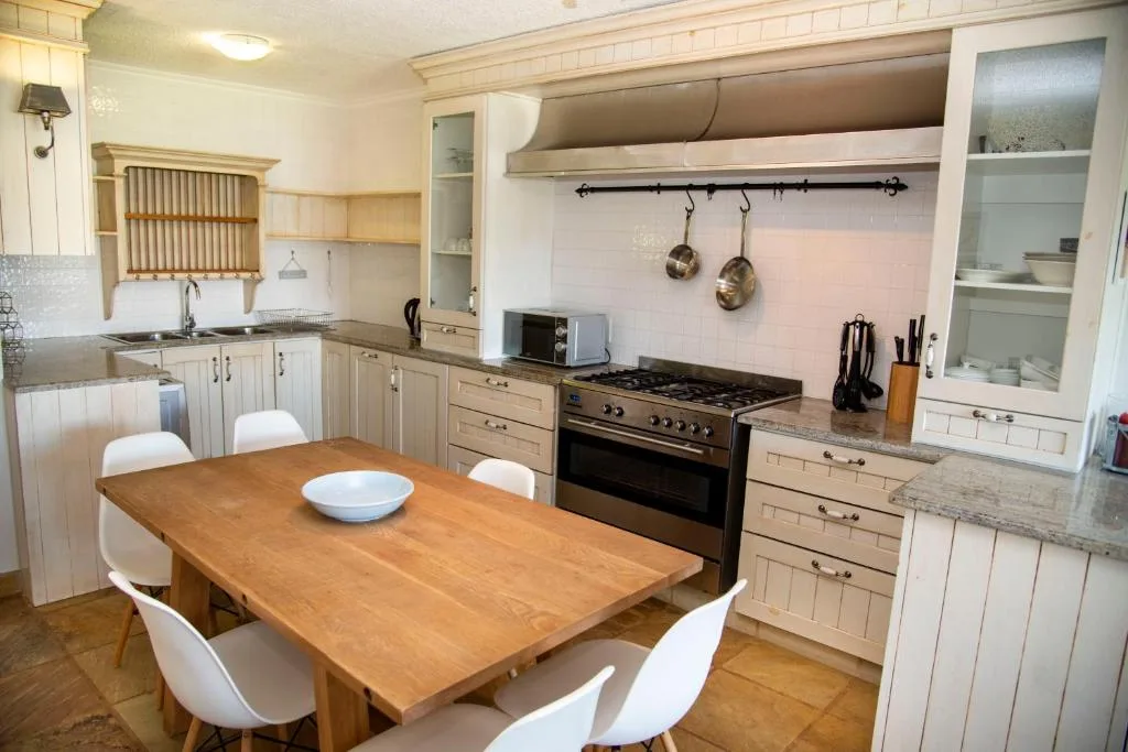 Spacious kitchen with cream cabinetry, gas range, and wooden dining table