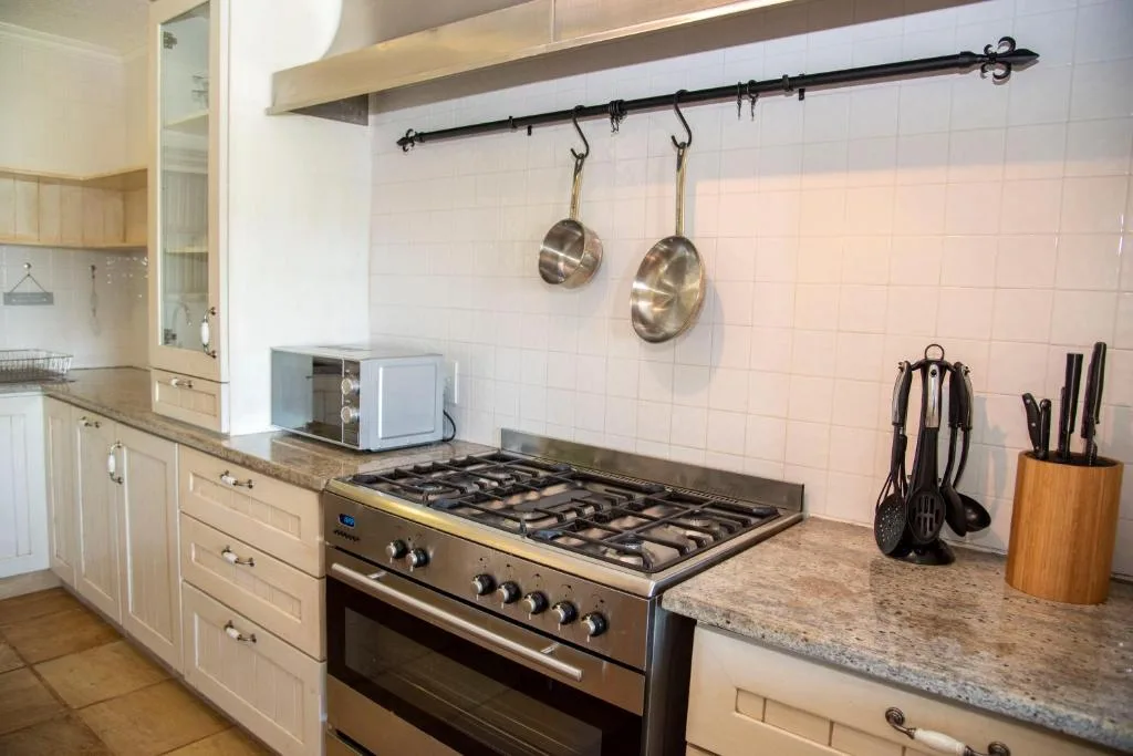 Well-equipped kitchen with gas stove, granite counters, and hanging cookware