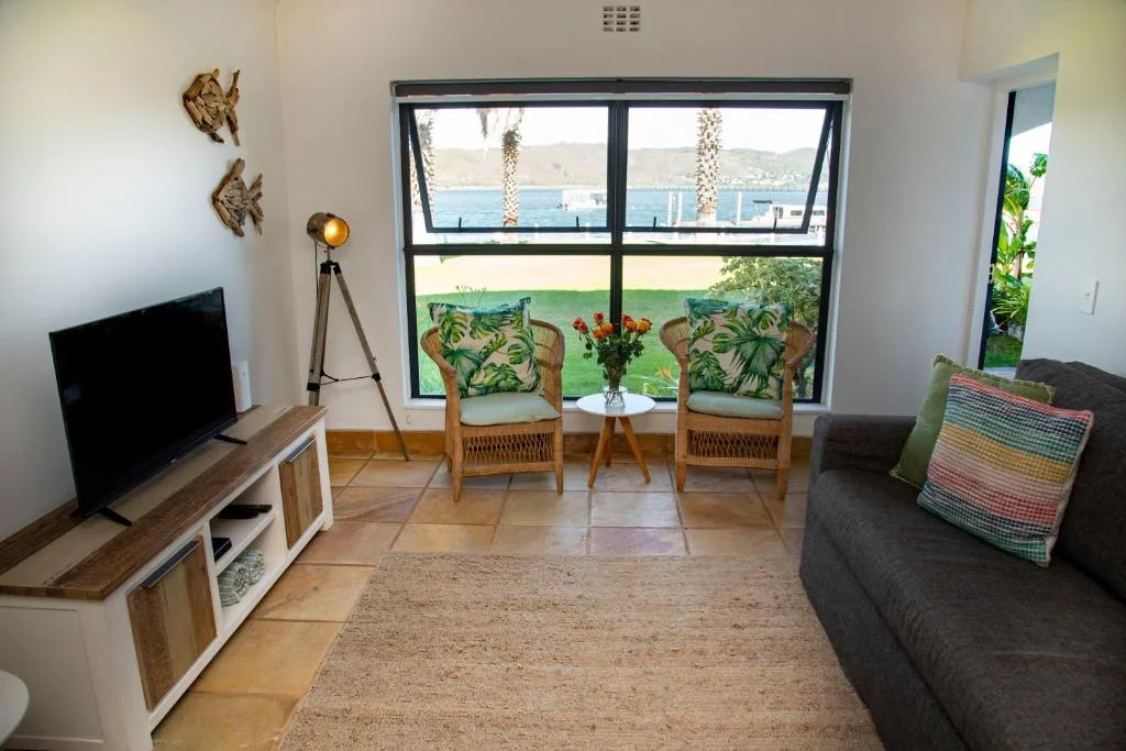 Spacious lounge with water views, TV, sofa, and seating chairs