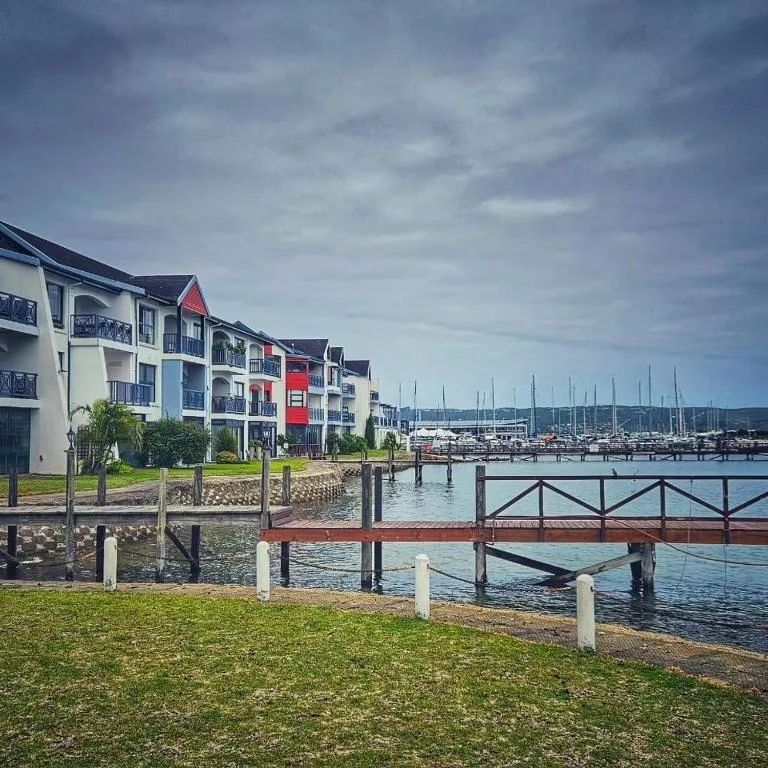 Waterfront apartment building overlooking Knysna Lagoon with sailboats and dock