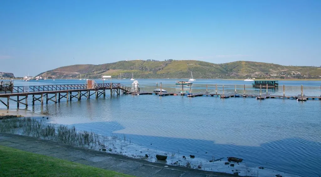 Scenic lagoon waterfront with wooden jetties, boats, and green hills
