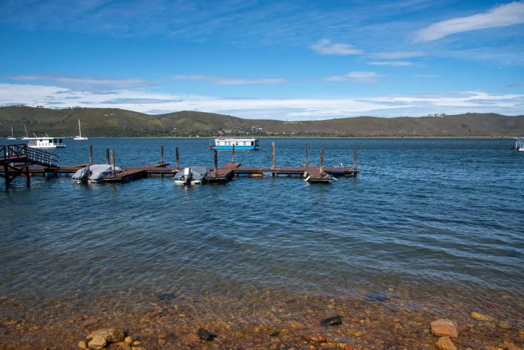 Scenic lagoon view with moored boats and green hillsides under blue sky