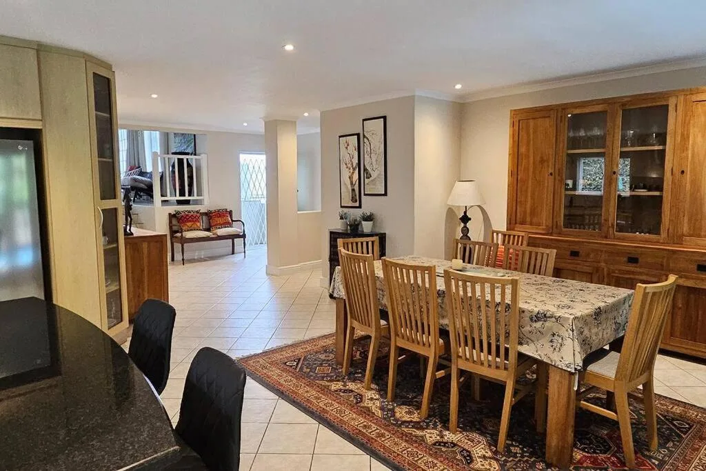 Spacious dining area with wooden table and chairs, opening to kitchen and lounge