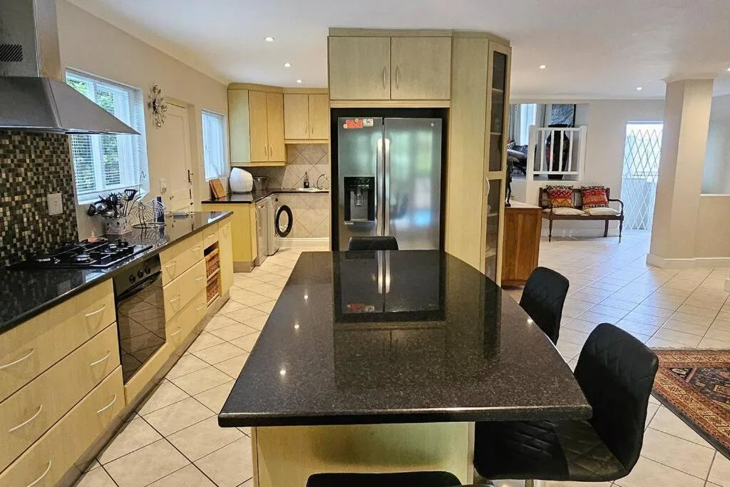 Spacious kitchen with light wood cabinetry, black granite island, and stainless steel appliances