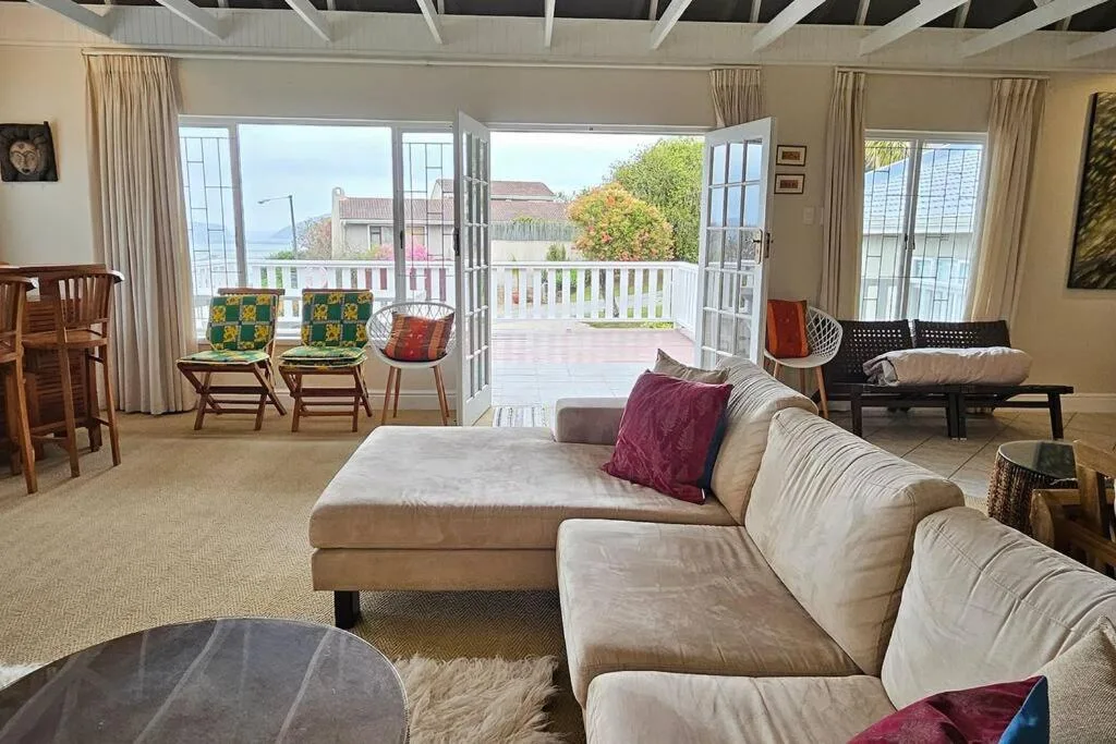 Spacious living room with cream sofa, deck views, and coastal landscape