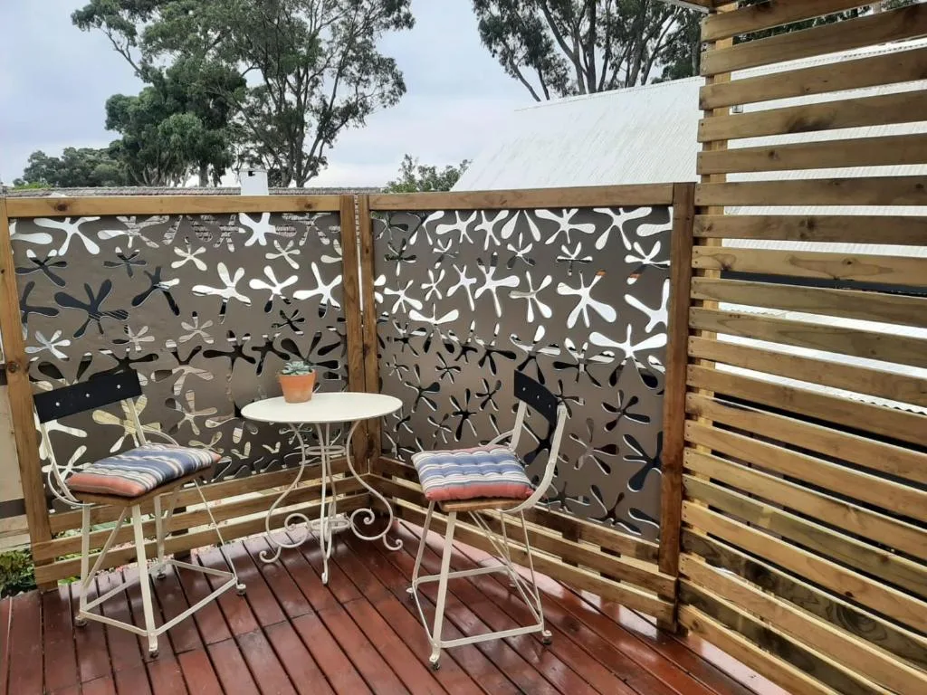 Shaded outdoor seating area with decorative screens and comfortable chairs