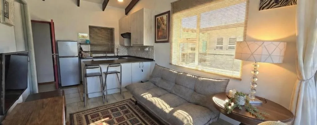 Open-plan lounge with gray sofa and kitchen area visible in background