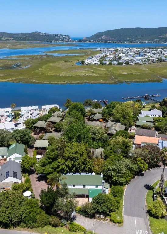 Aerial view of Knysna lagoon with white waterfront homes and green hills