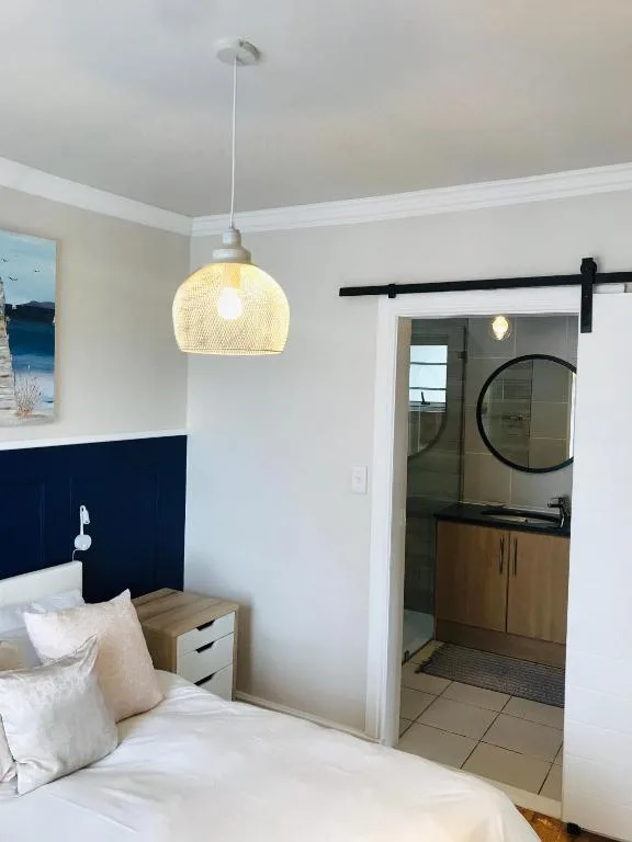 Modern bedroom with pendant light, navy headboard, and ensuite bathroom access