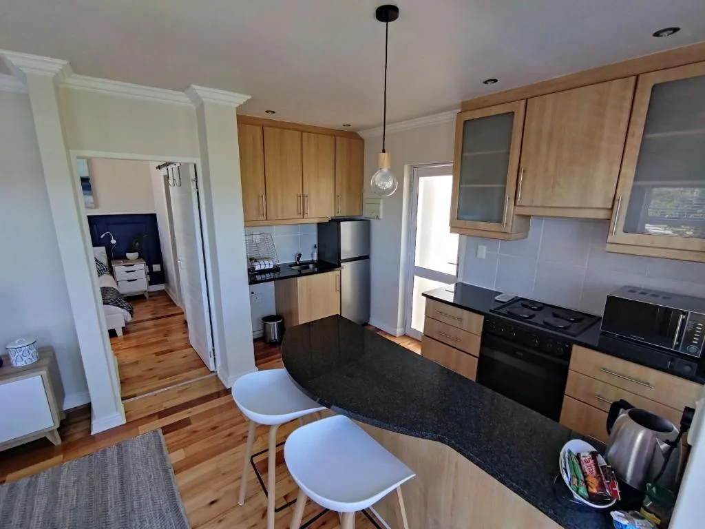 Modern kitchen with wooden cabinetry, black countertops, stainless steel appliances