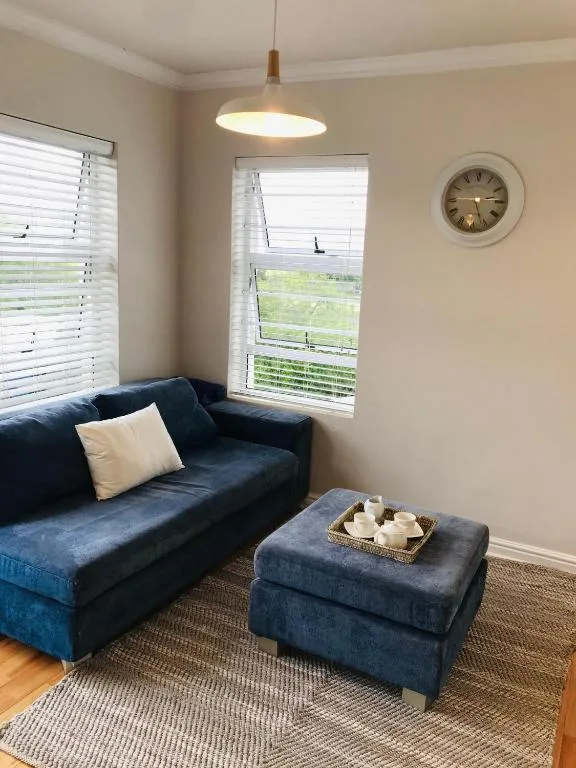 Cozy lounge with blue sofa, ottoman, and garden views through large windows