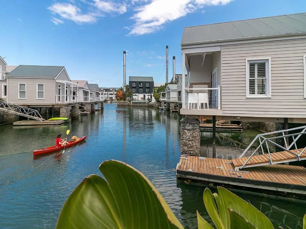 Waterfront canal village with modern cottages, wooden decks, and kayaks on water