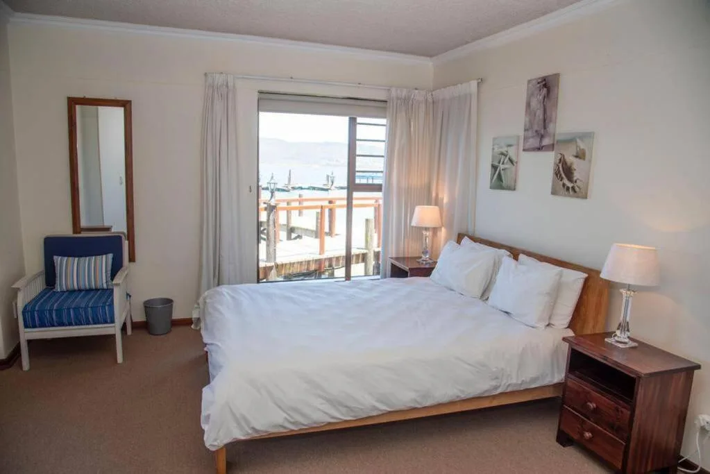 Bright bedroom with queen bed, sea view through glass doors, coastal decor