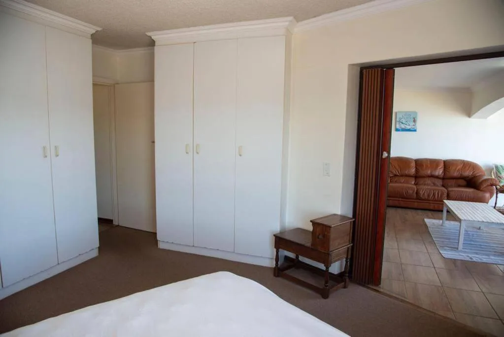 Spacious bedroom with white built-in wardrobes and wooden side table