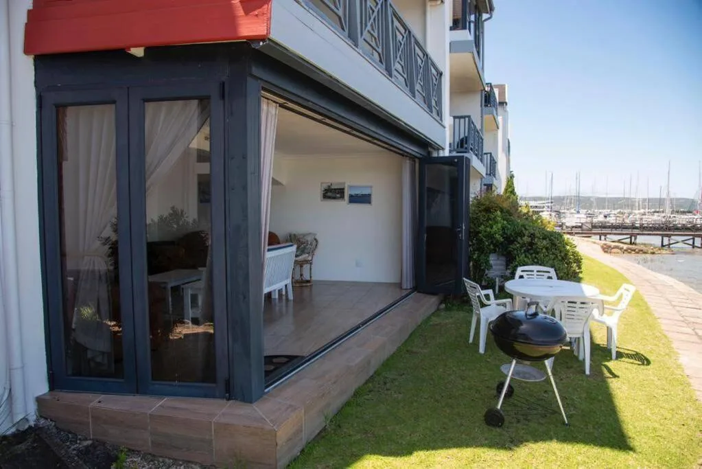Waterfront patio with lounge chairs, braai grill, and marina views beyond
