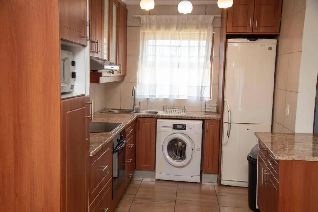 Modern kitchen with wooden cabinetry, granite counters, and stainless steel appliances