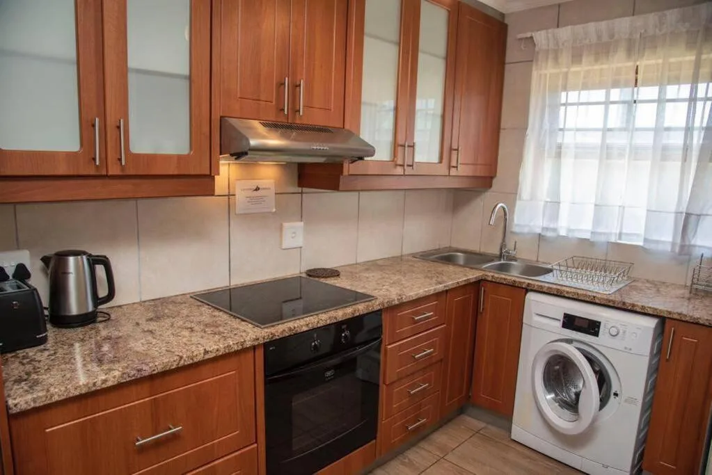Modern kitchen with wooden cabinetry, granite countertops, and stainless steel appliances