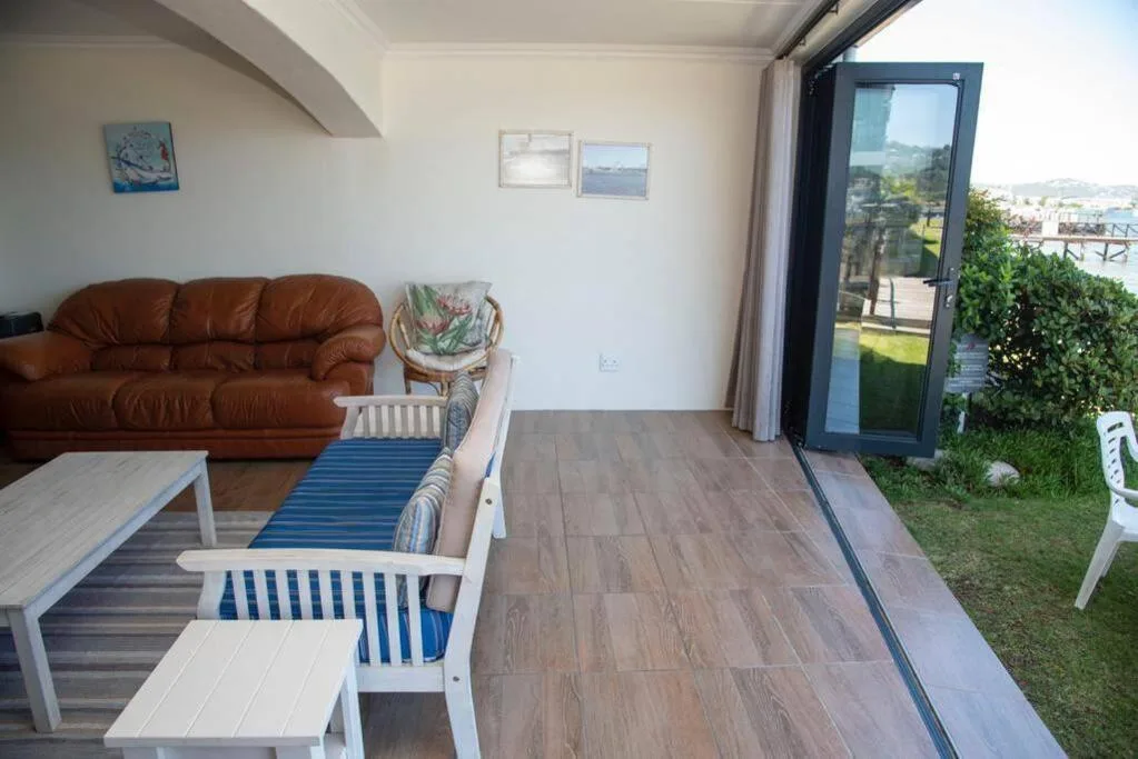 Open-plan lounge with brown leather sofa and blue striped chairs, opening to deck