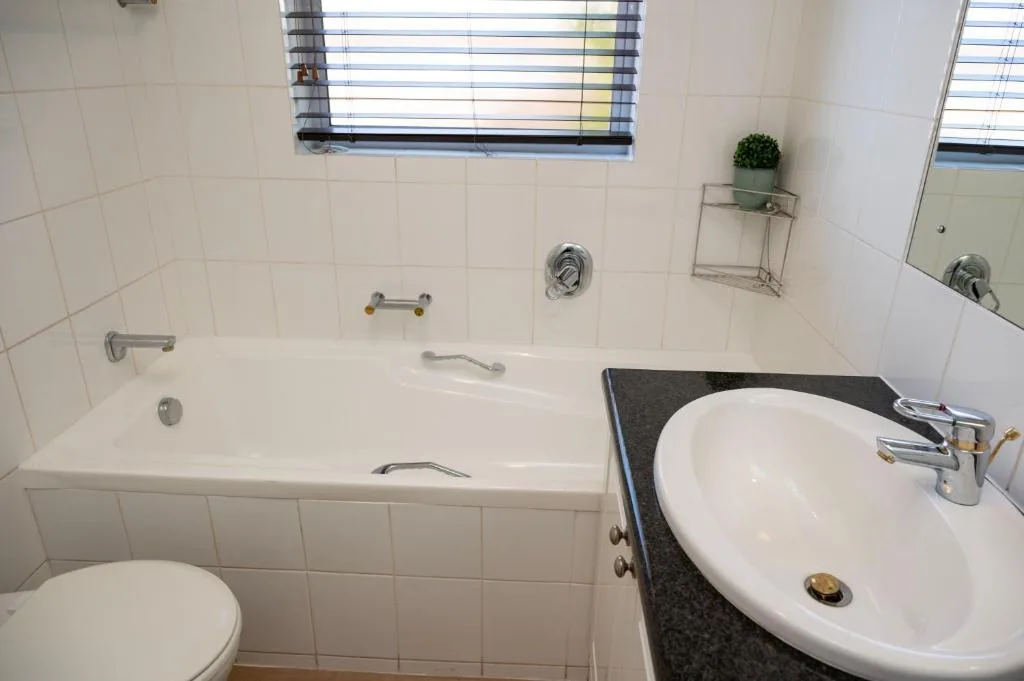 Clean bathroom with bathtub, round sink, toilet, and natural light