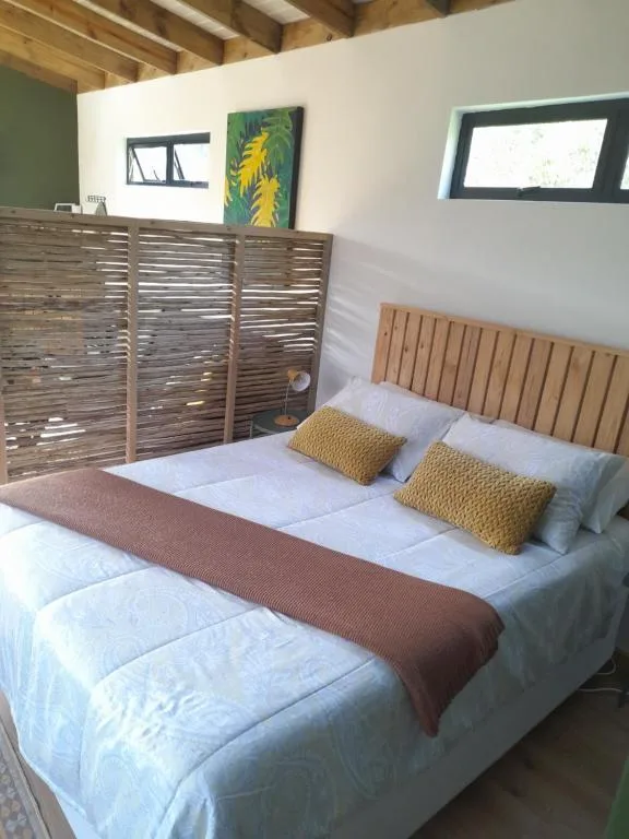 Spacious bedroom with queen bed, yellow accent pillows, wooden headboard
