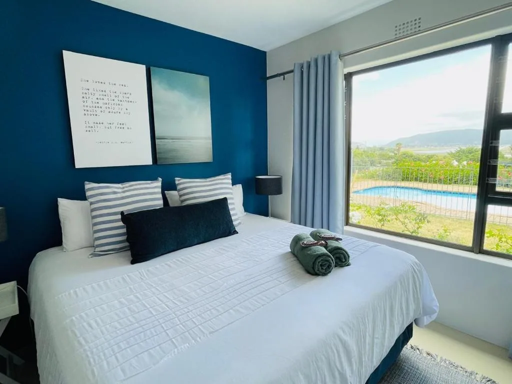 Modern bedroom with blue walls, striped pillows, and scenic mountain view through glass doors
