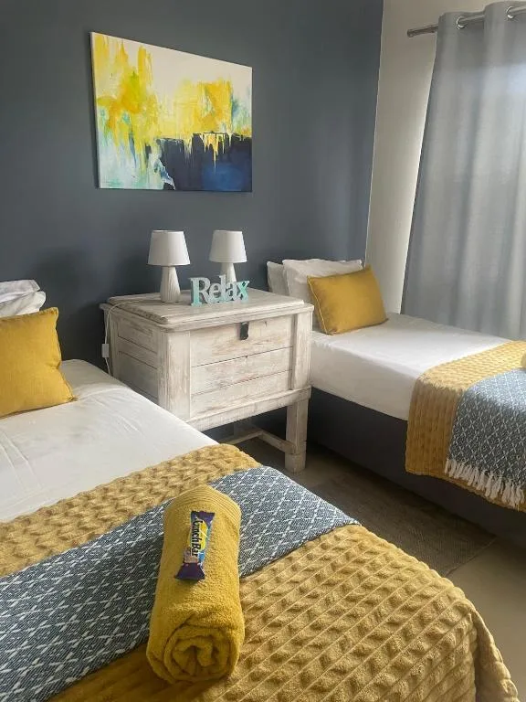 Twin bedroom with yellow accents, wooden nightstand, and modern artwork