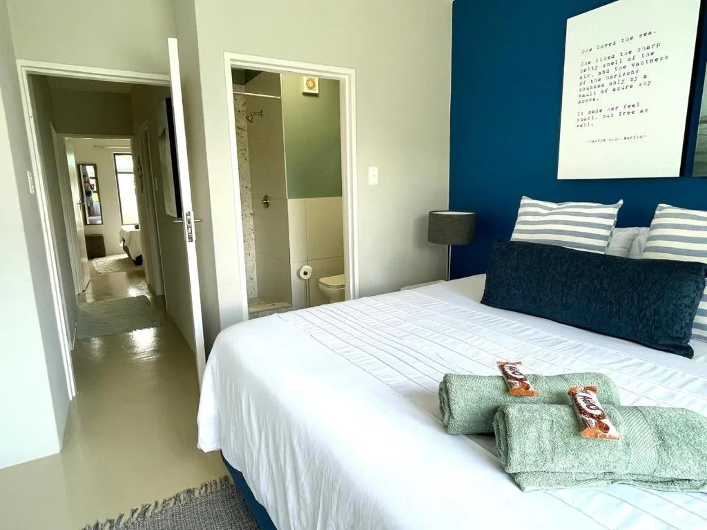 Modern bedroom with queen bed, striped pillows, and ensuite bathroom visible