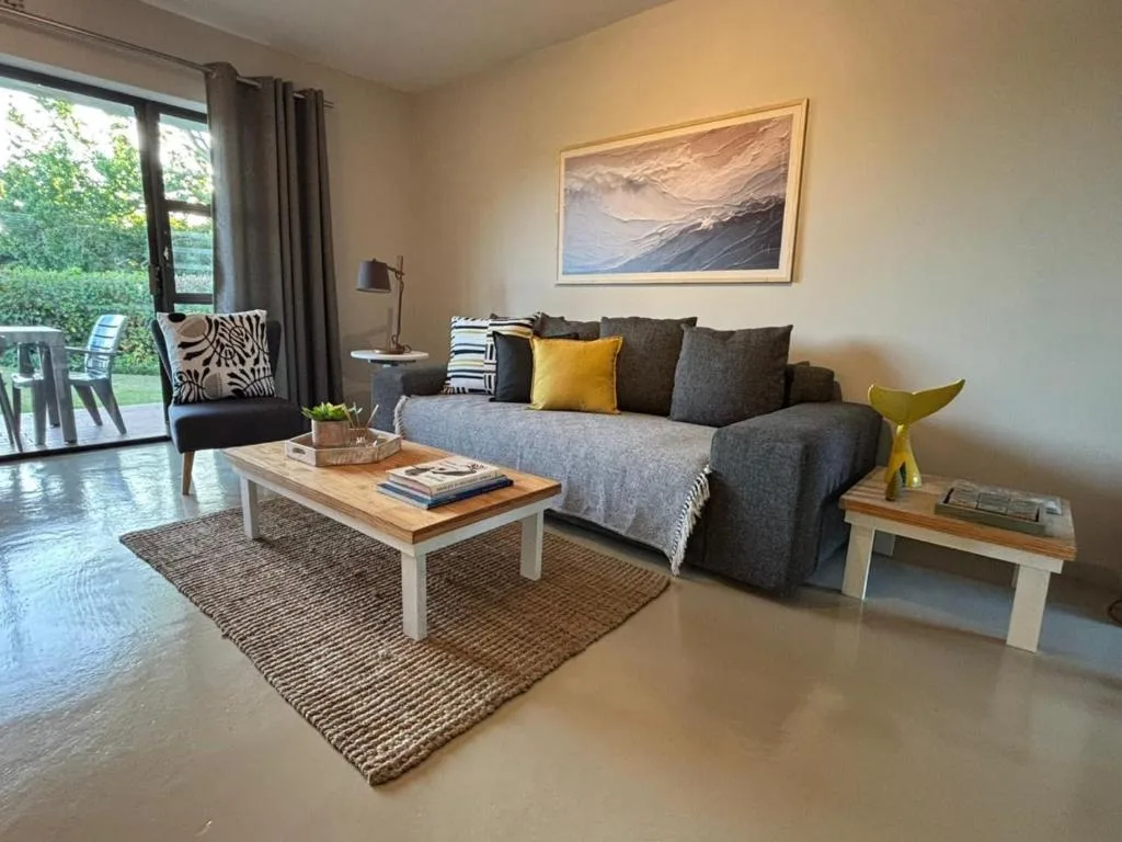 Spacious lounge with gray sofa, coffee table, and garden views through glass doors