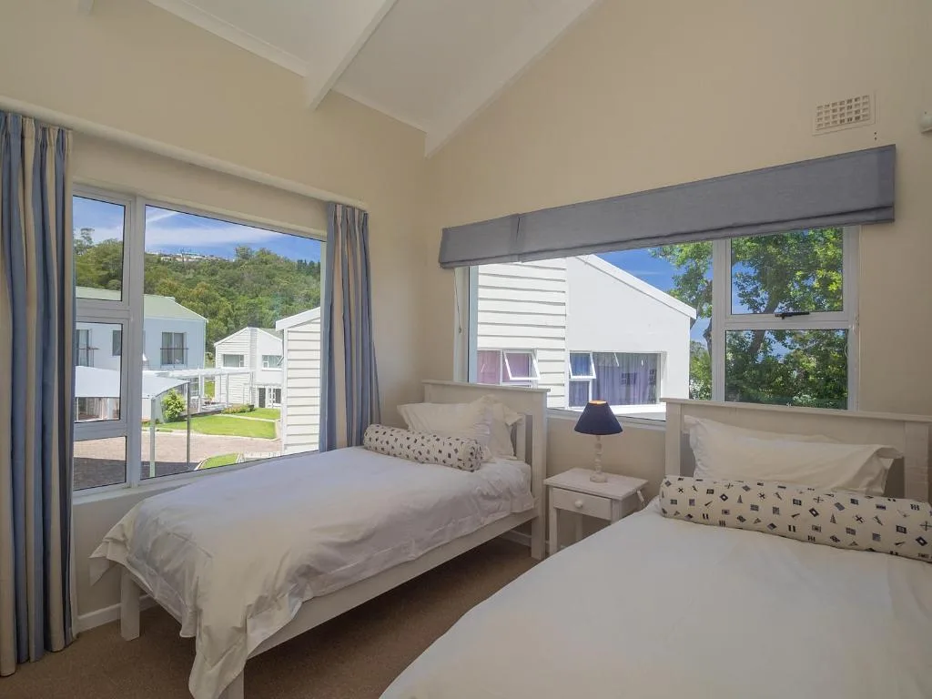 Bright bedroom with two single beds and large windows overlooking gardens